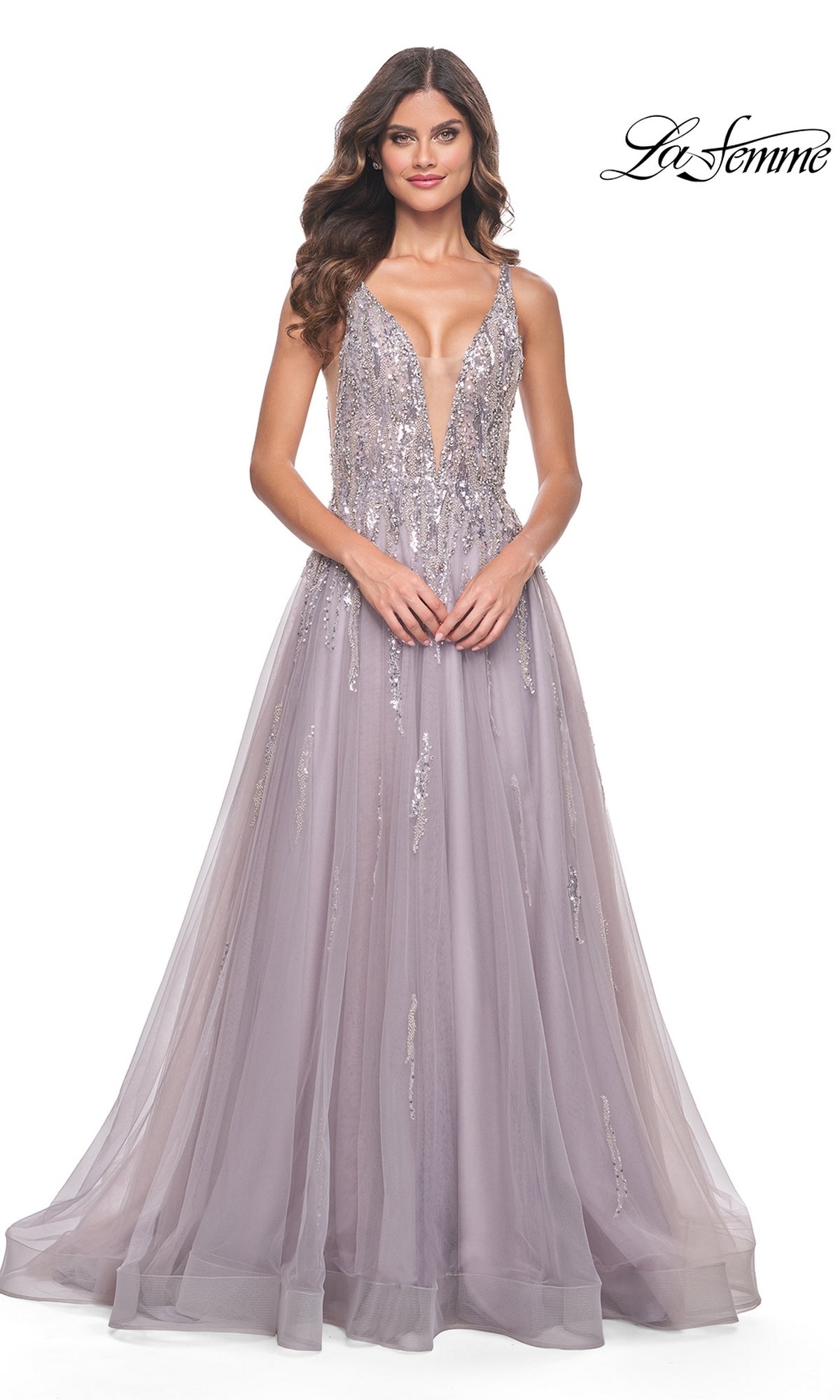 A woman models the Sequined Long Mauve Prom Dress: La Femme 31995, featuring a floor-length tulle skirt, deep V-neckline, and sparkling sequin embellishments, against a plain white background.